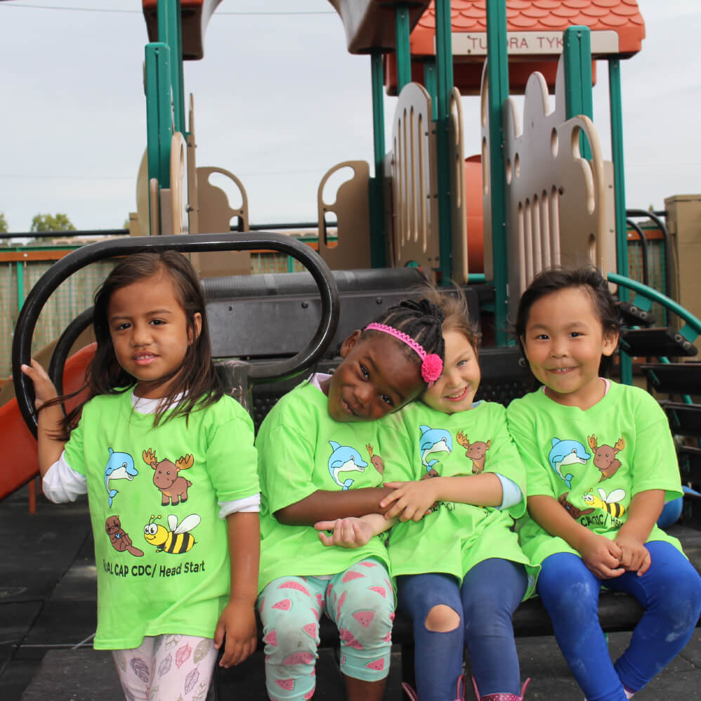 Four children posing in front of a playground